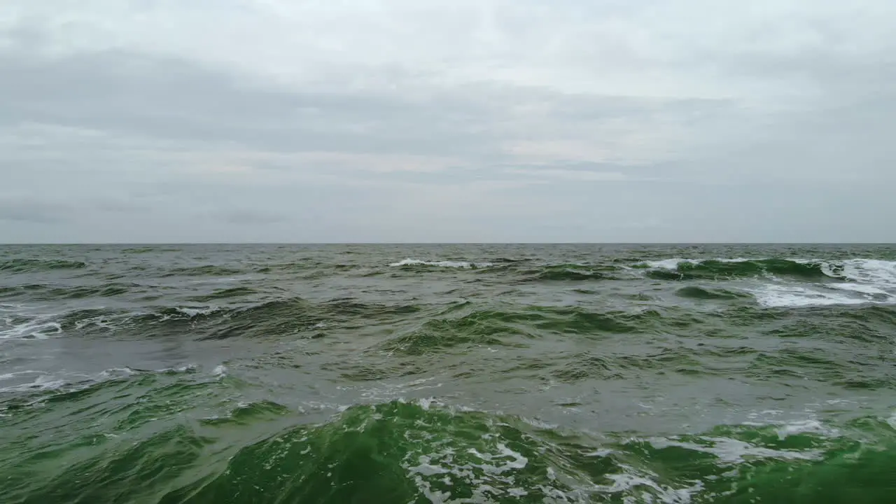 Dark green and wild sea waves captured by a drone on a cloudy windy day