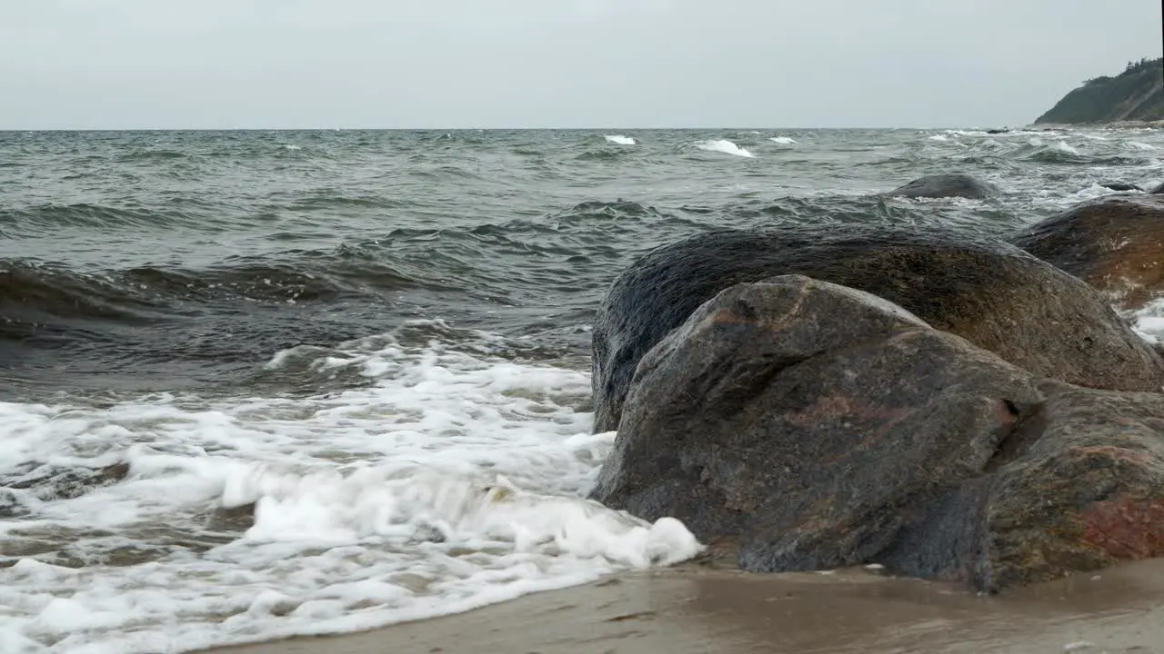 Waves rolling and crashing into rocky shore on overcast day