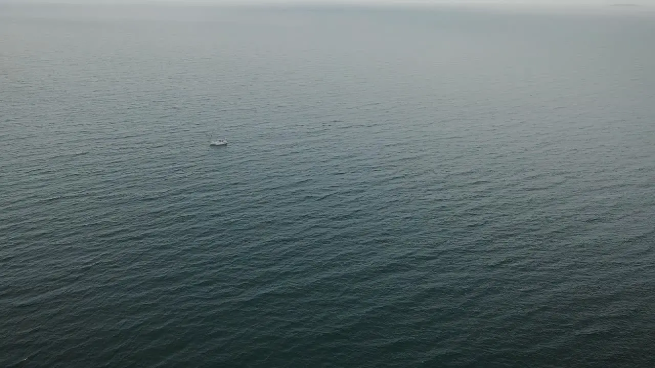 Super wide high aerial view of small sailboat in middle of vast sea