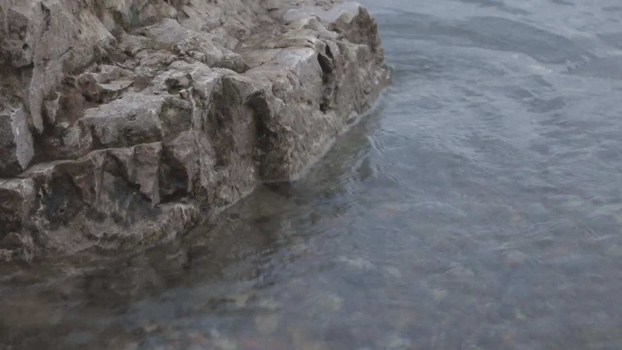 Clear seawater with soft waves moving towards a rocky shore medium shot