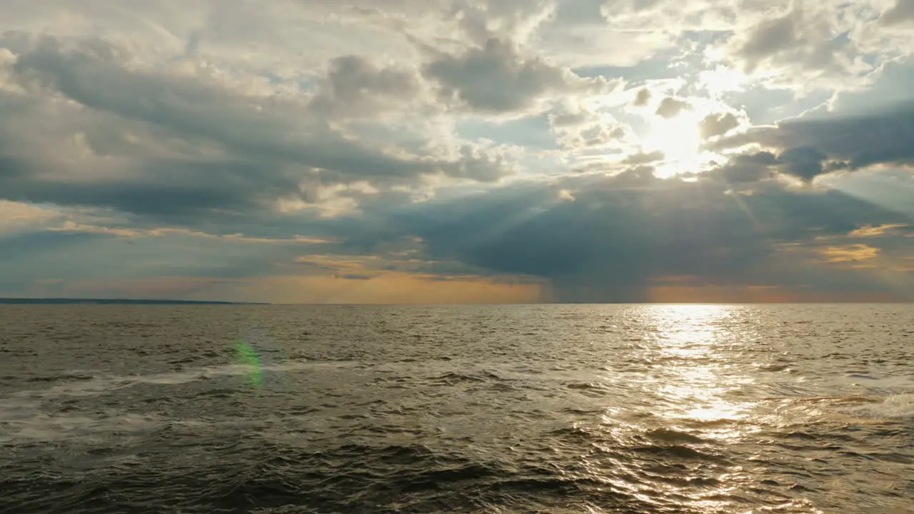 A Rain Cloud With Rain Over The Sea And A Setting Sun With Beautiful Rays 1