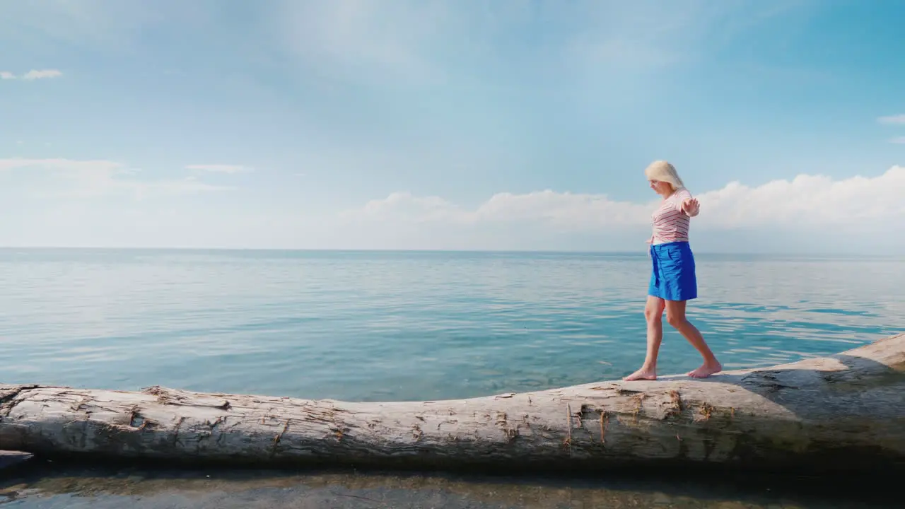 A Focused Woman Walks Along A Log Maintains Balance With Her Hands