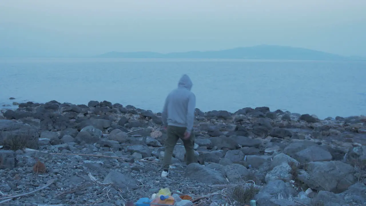 Male youth throws plastic on seaside shoreline from pocket