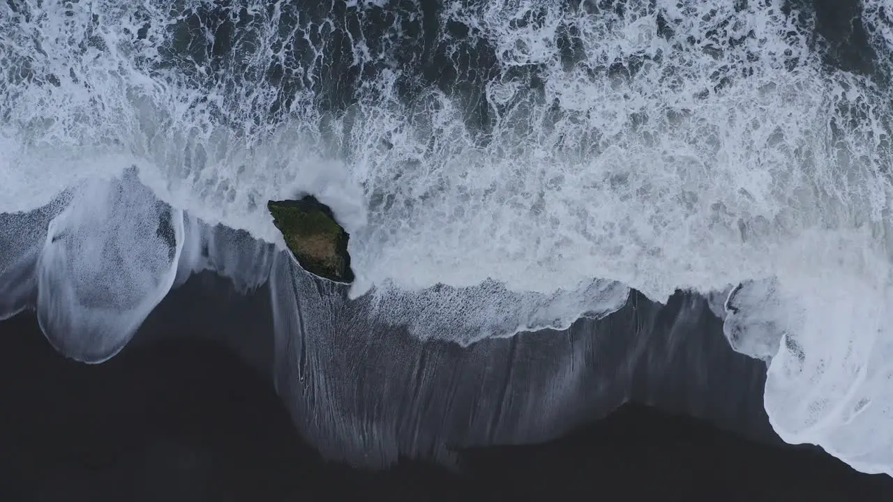 Foamy Coastal Waves Approaching The Black Sandy Shore With A Lone Rock In A Deserted Beach In Iceland