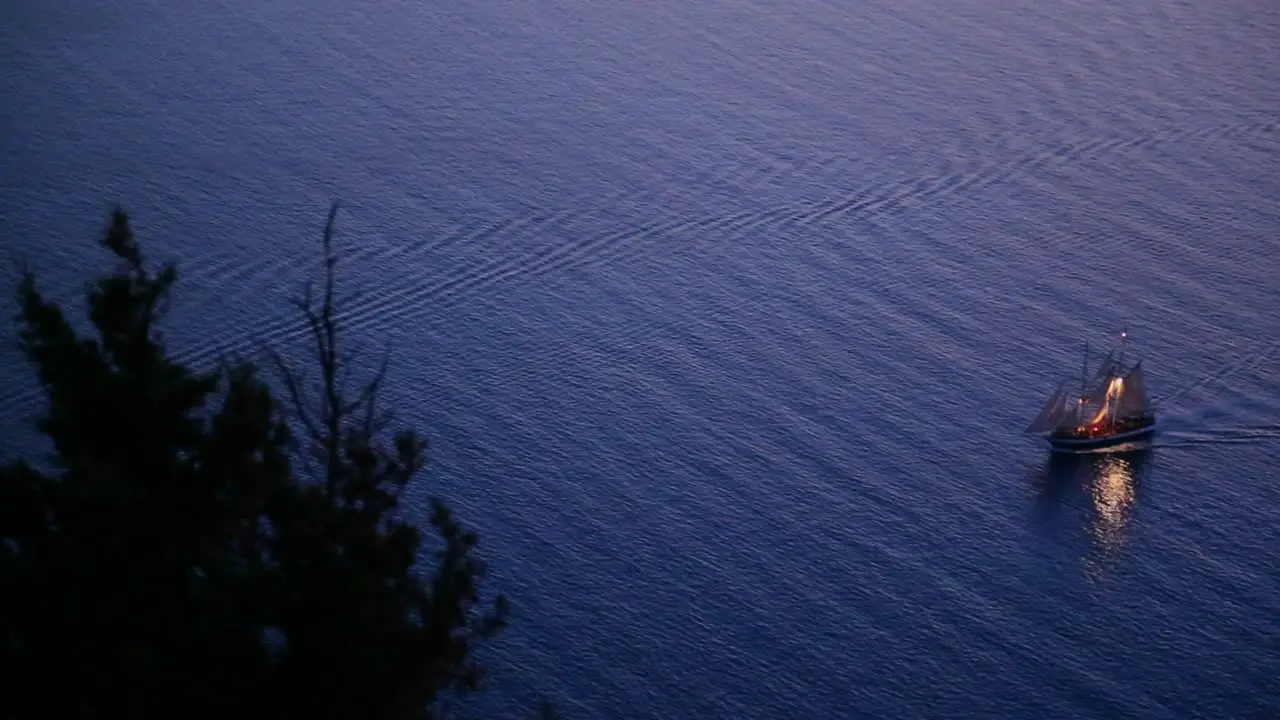 A beautiful sailing ship sails near a coastline at night