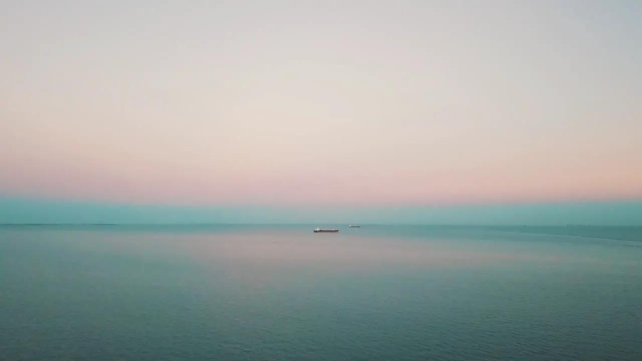 Drone flying above the sea with the cargo ship in the background at the sunset-1