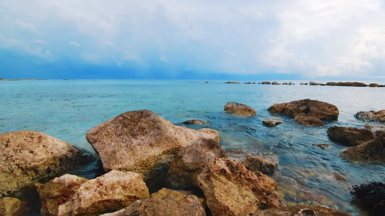 SLOWMO water lapping ocean rocks heavy storm clouds in background Caribbean