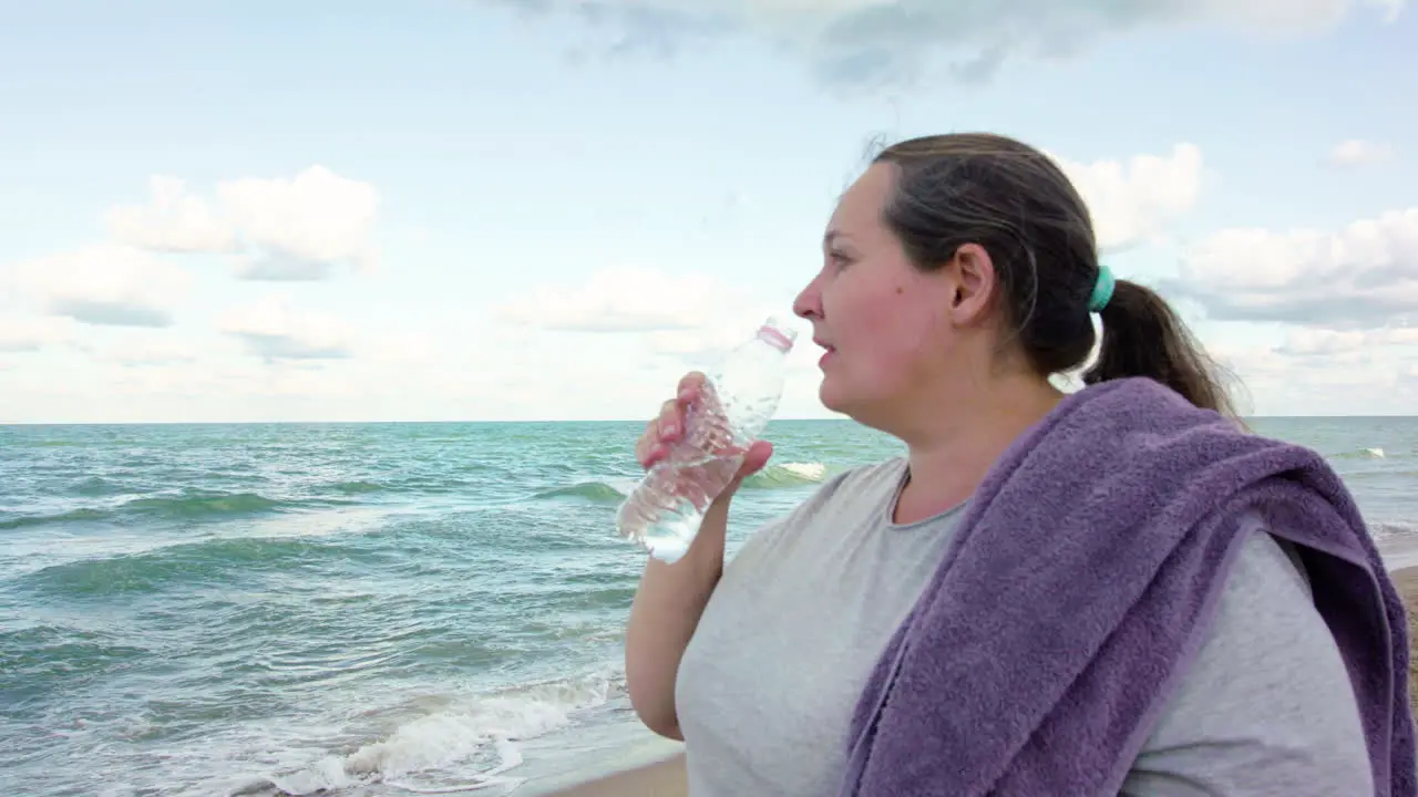 Chubby girl drinking water on the beach