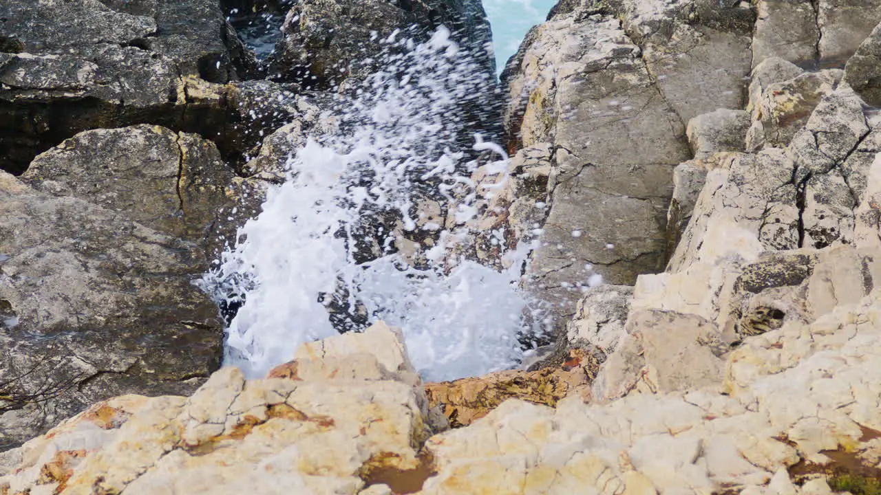 Sea waves breaks through hole in rocky shore