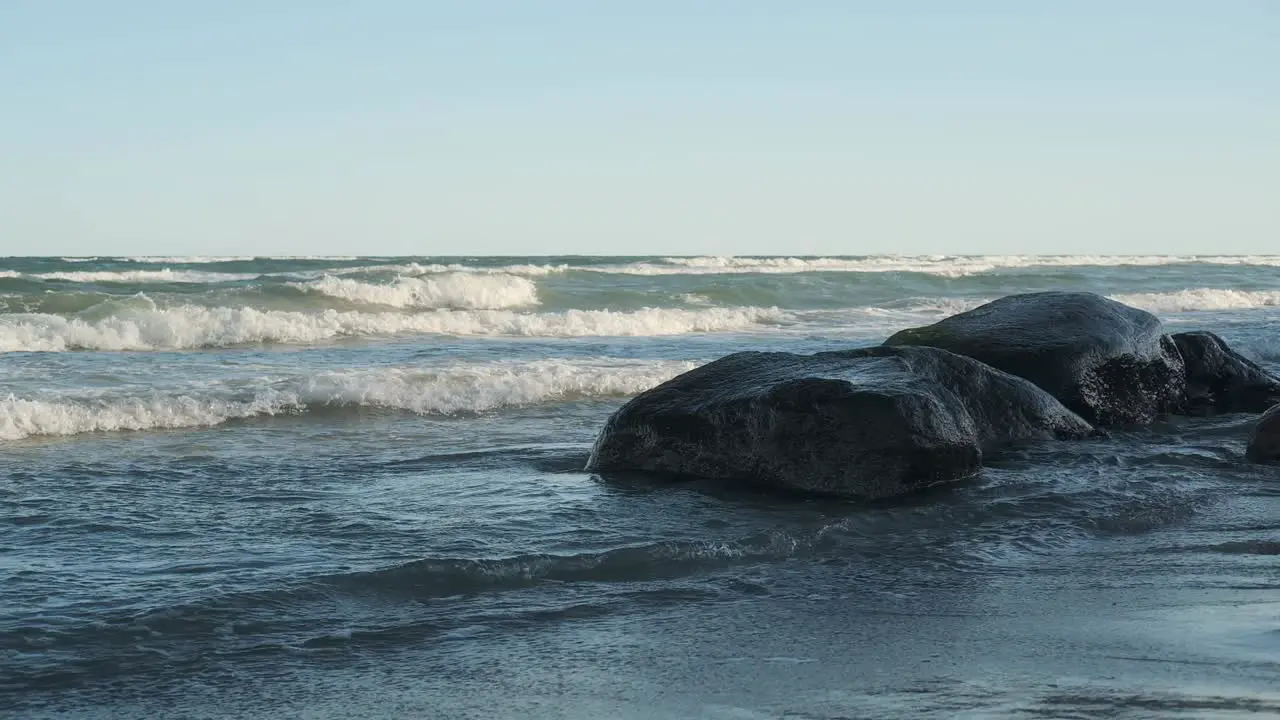 Wavy sea and stones in morning sunlight slow motion