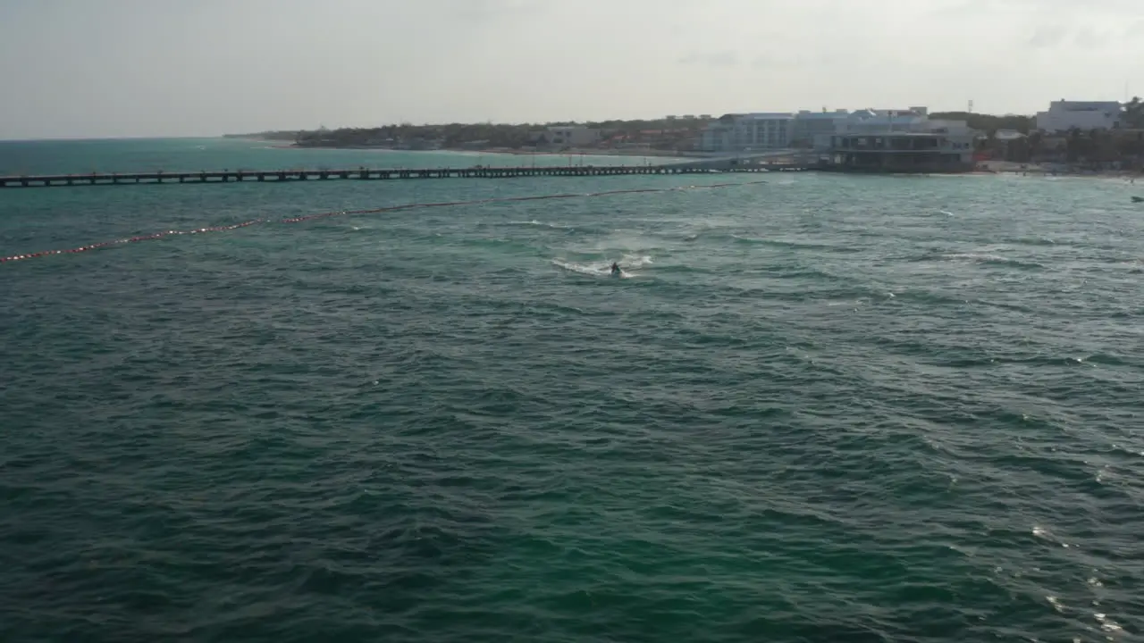 Aerial view with two males riding the waves with jet ski on Caribbean Sea The beach at Playa del Carmen in background