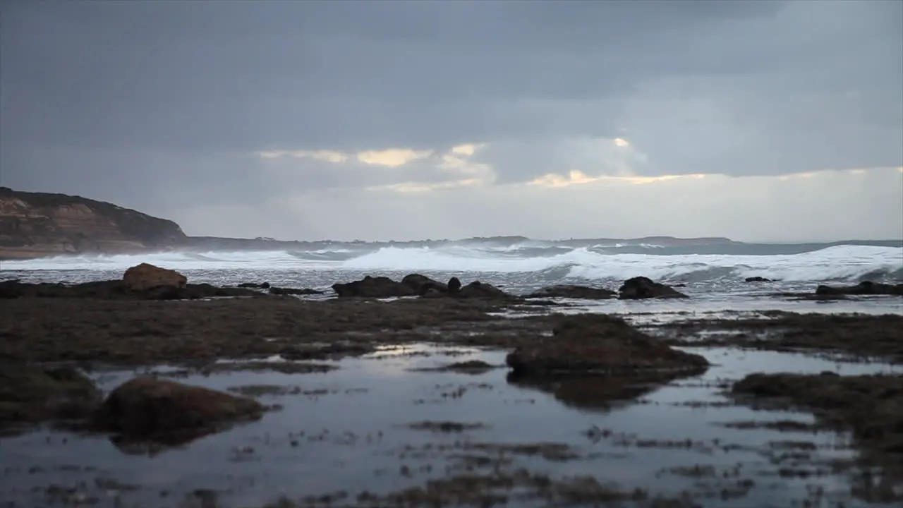 Waves rolling towards shore in the distance with rock pools in the foreground