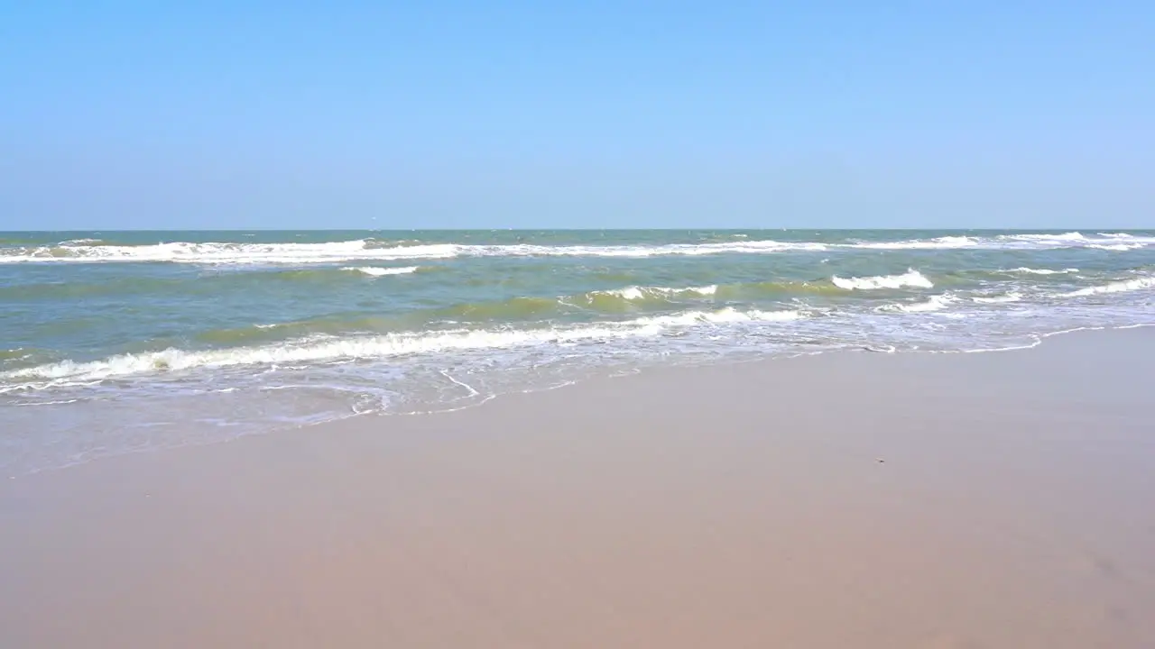 Waves roll in and recede along the edge of a sandy beach