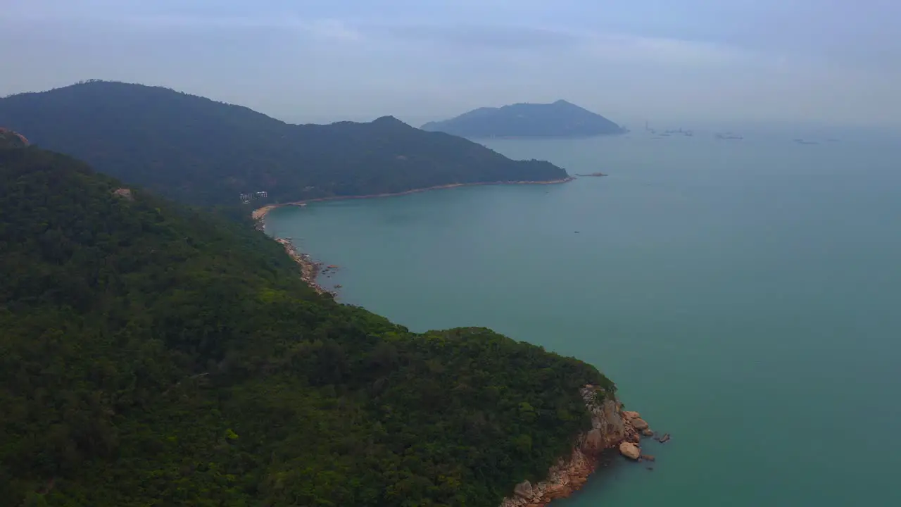 drone shot of a mountain coast full of vegetation and cliffs during the day