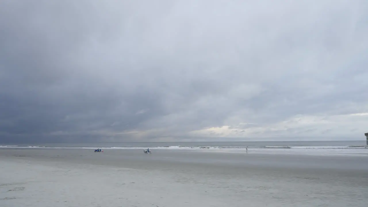 Storm brewing above wide shot of beach waves breaking in distance