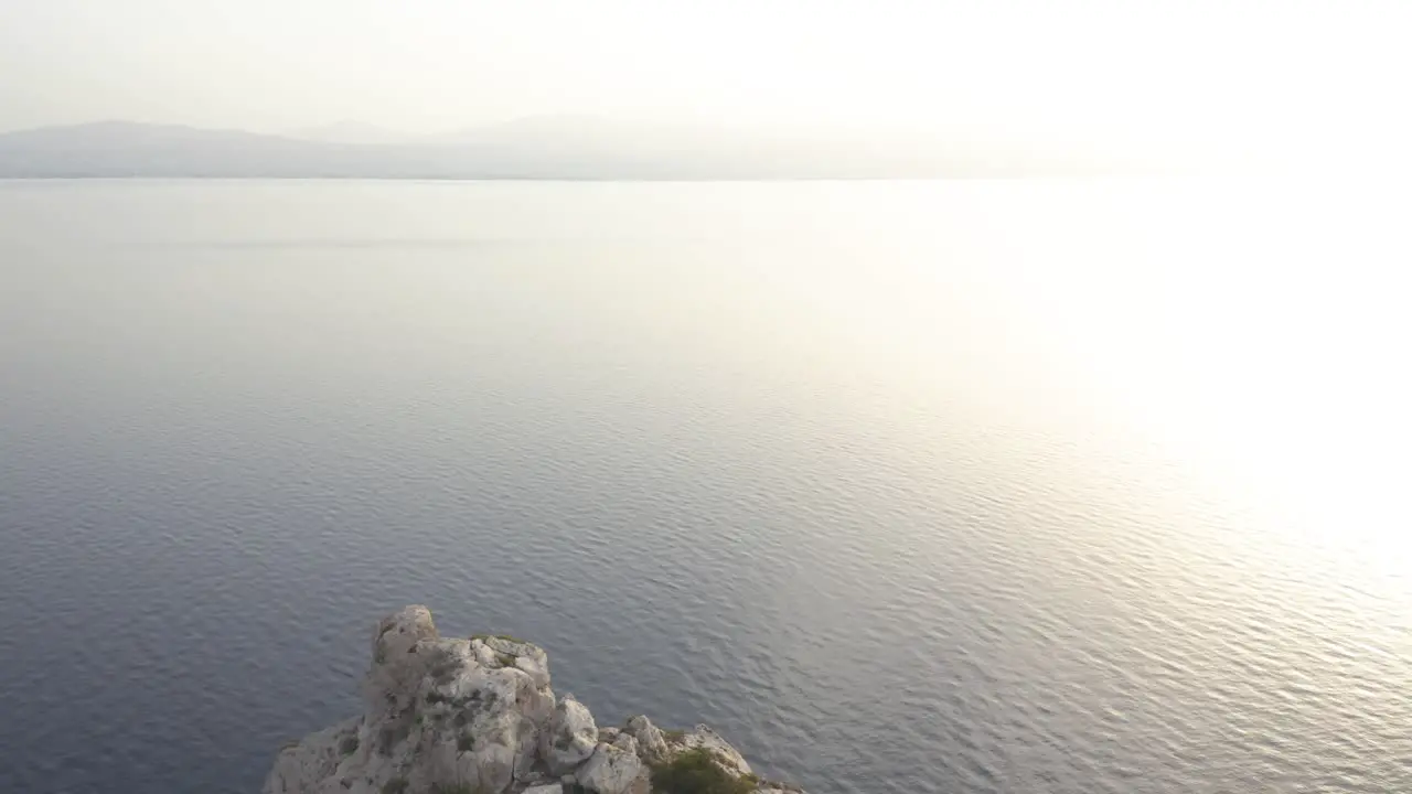 An aerial drone forward move from a lighthouse in the edge of some cliffs towards the sea