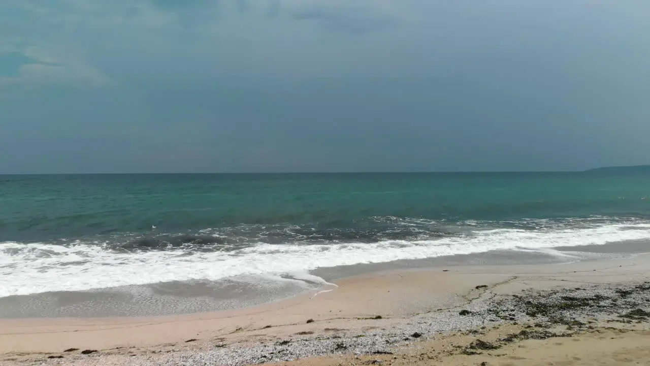 Drone flying low to the beach towards the sea cloudy sky dark water Sozopol Bulgaria