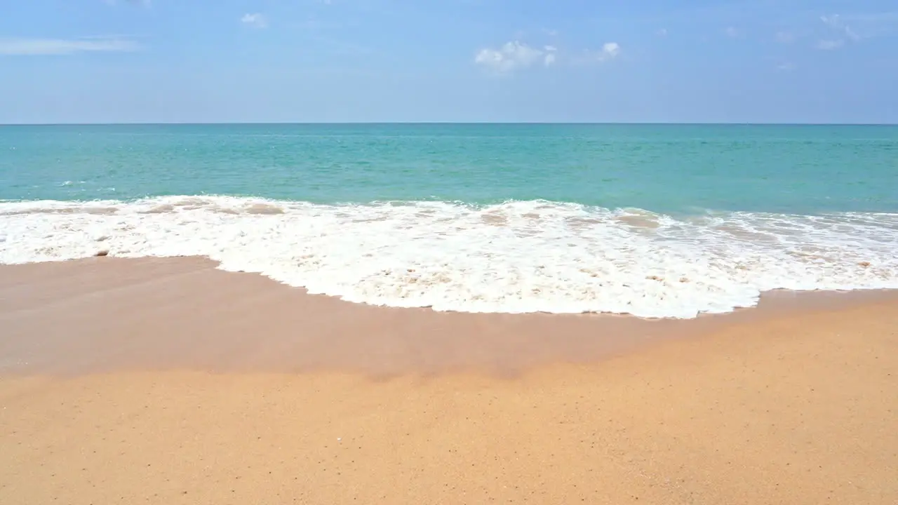 Slow-motion of a large wave spreading across the golden sand of a deserted beach