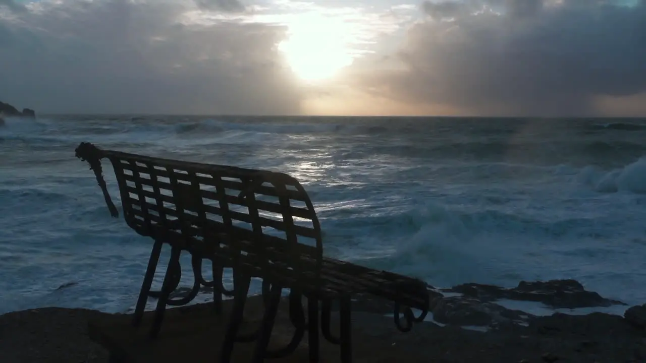 Rusty metal bench overlooking a stormy sea with a dark cloudy sky