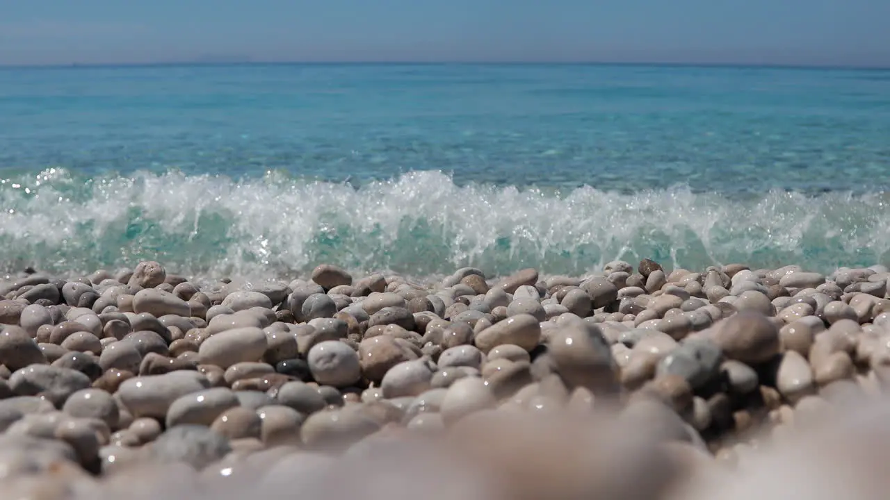 Emerald sea water splashing on pebbles beach on a vacation day in Mediterranean