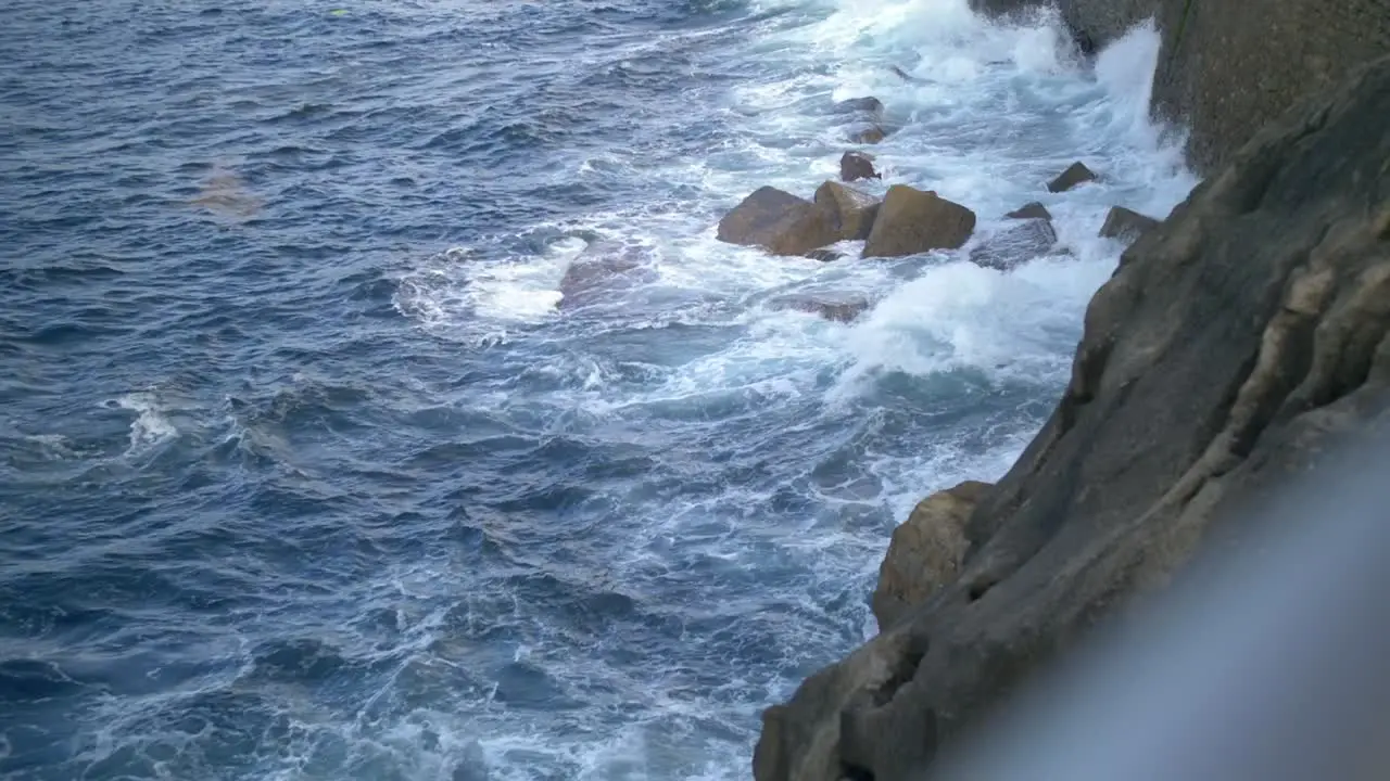 Waves crashing against the rocks on a European shoreline of a during sunset in San Sebastian Spain handheld shot