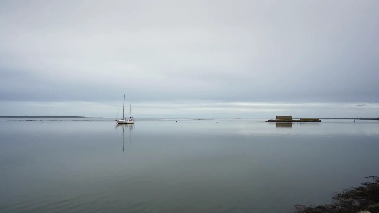 Lonely boat on water beside small island grey day horizon