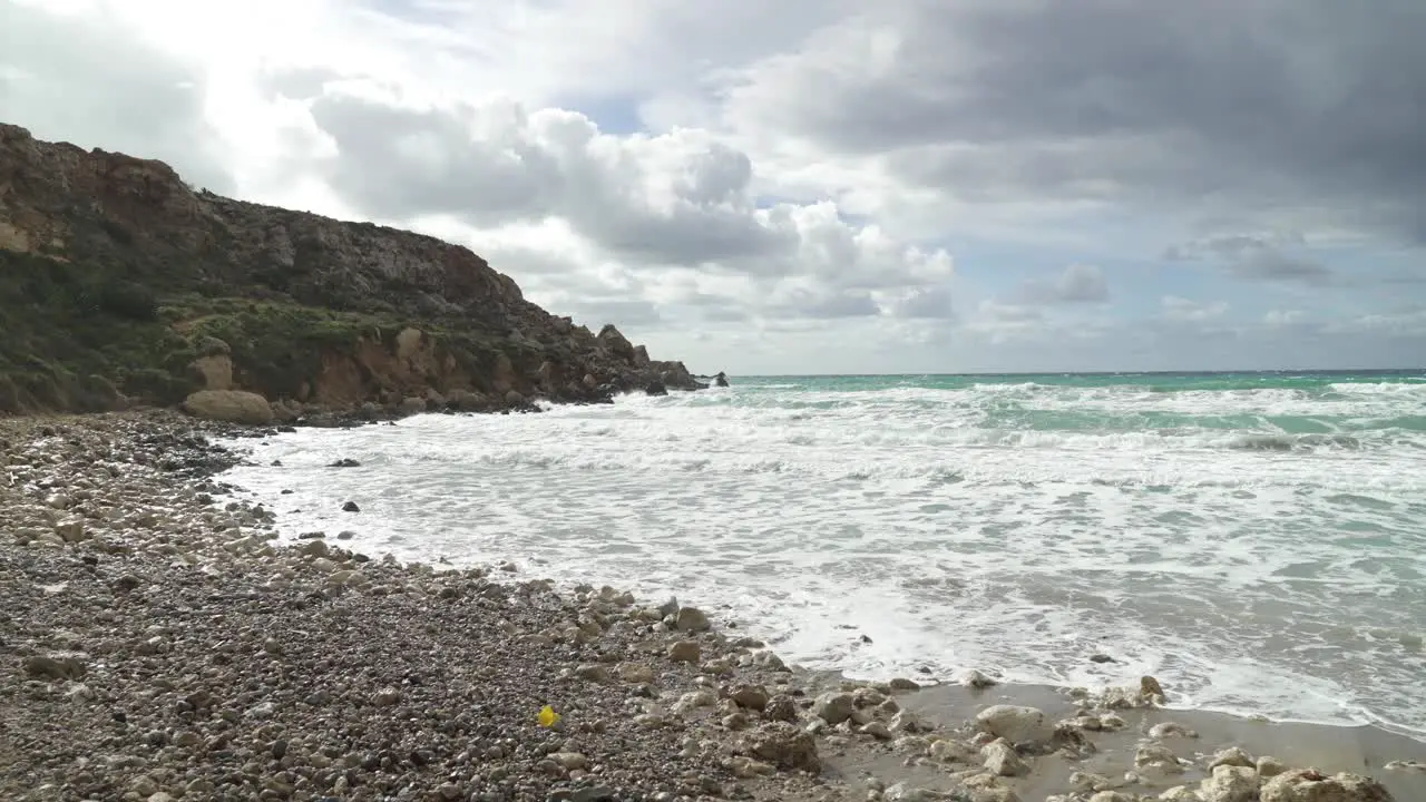 Piles of Rocks On a Golden Bay Beach with Mediterranean Sea Waves Crashing on Sandy Shore