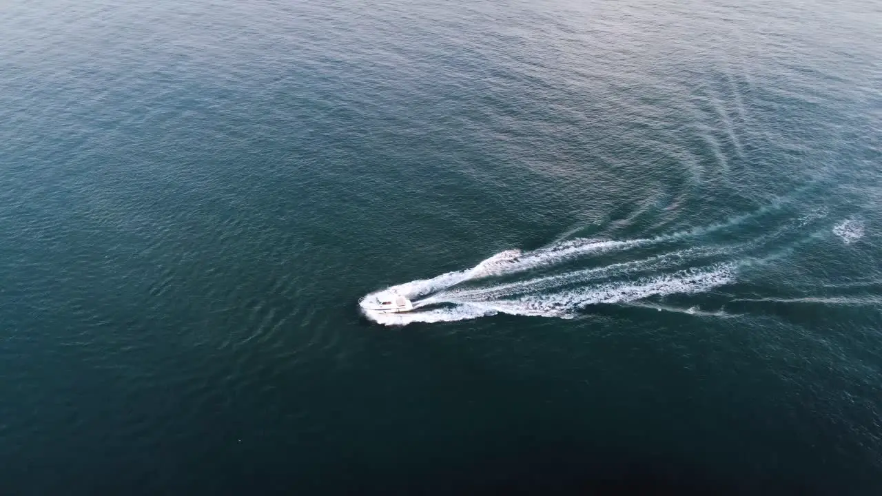 Drone view of boat sailing to the left on open ocean on a warm sunny summer day in the Faroe Islands