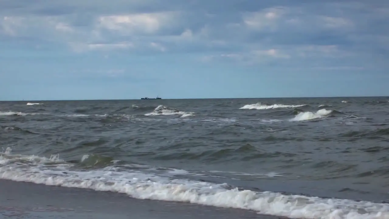 The sea waves shore and a large ship at sea