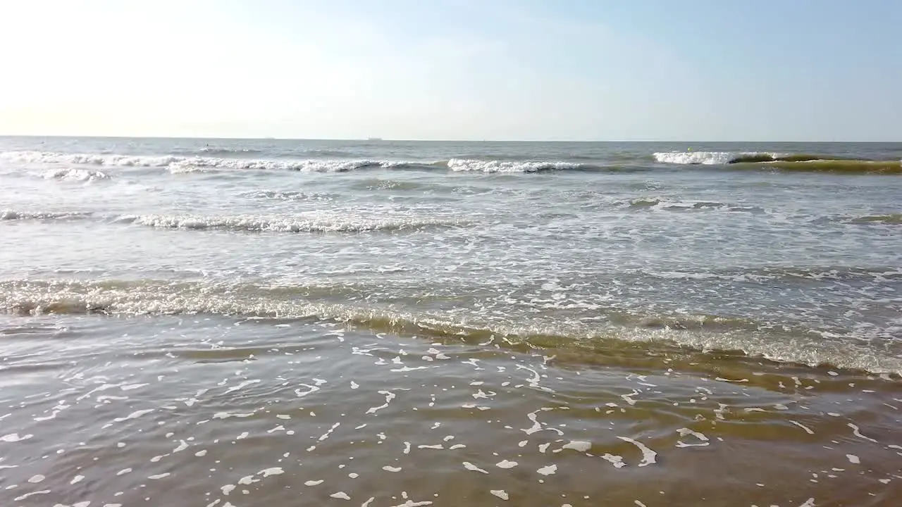 Beautiful video of a beach from the coastline during sunset while the waves crash the shore Belgium