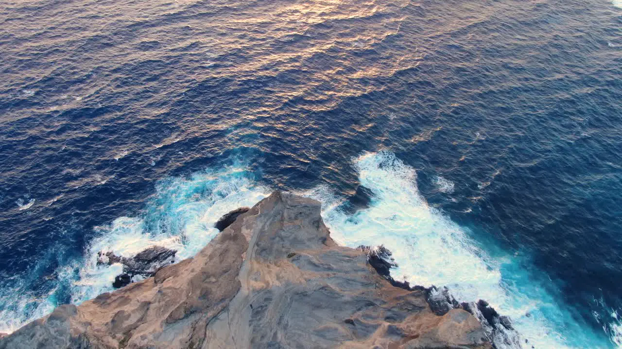 Aerial view of ocean waves crashing on a rocky mountain