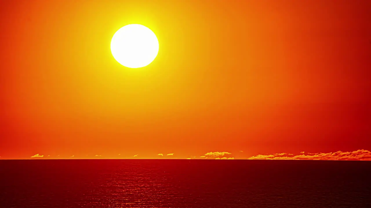 Bright shining sun setting behind ocean horizon during golden sunset at sea time lapse