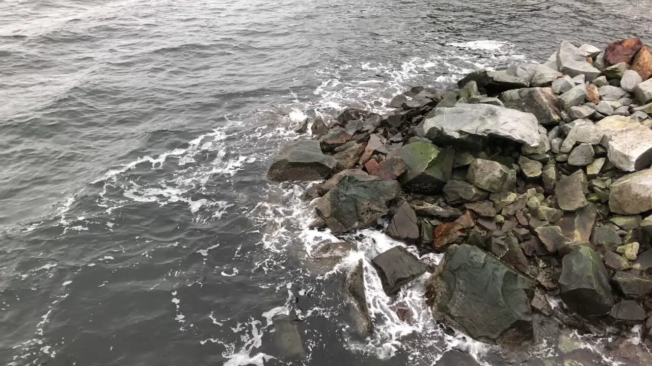 Water hits bedrock on shoreline slow motion long shot