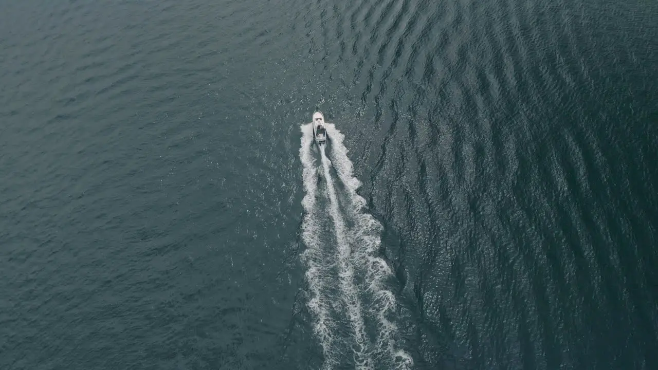 Aerial shot of with a drone following a boat from a distance