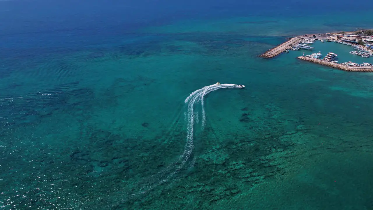 Areal shot of speed boat and towable water tube ring tourist action sport in Ayia Napa harbor marina