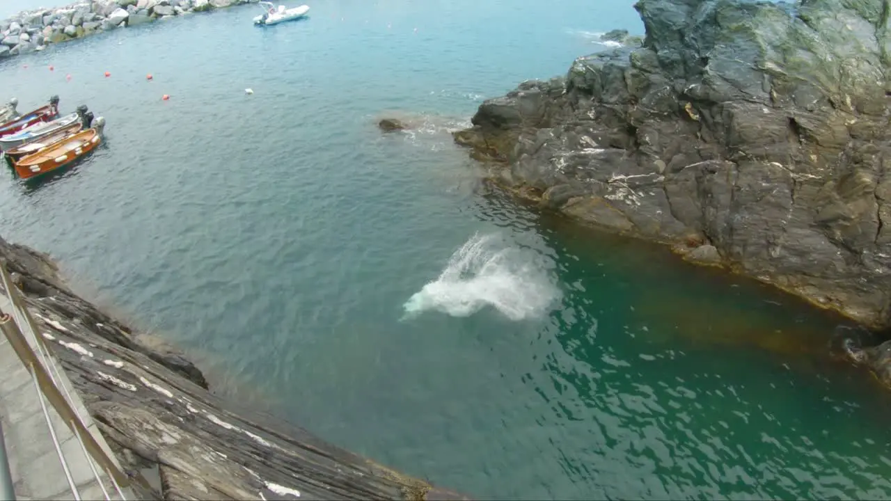 Young man jumping into water of coast of Manarola