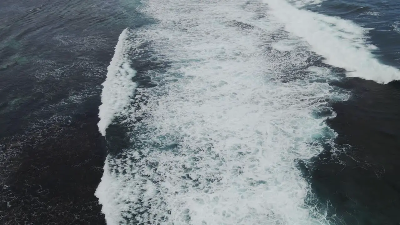 A dynamic aerial shot above large waves of water while moving its perspective upwards level to the horizon as it gradually descends