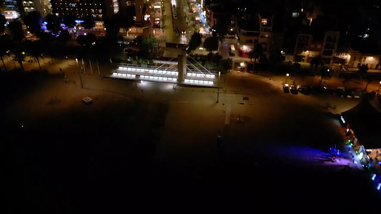 night view of the central street of calella and a beach bar with illuminated buildings and cars driving along