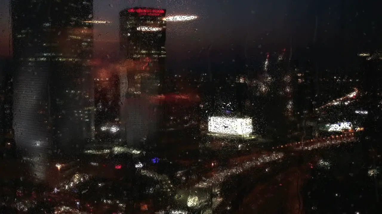 City skyline during the night seen through a rainy window skyscrapers of a city background