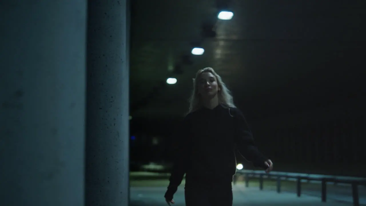 Night city woman walking confidently with blonde hair in underground tunnel