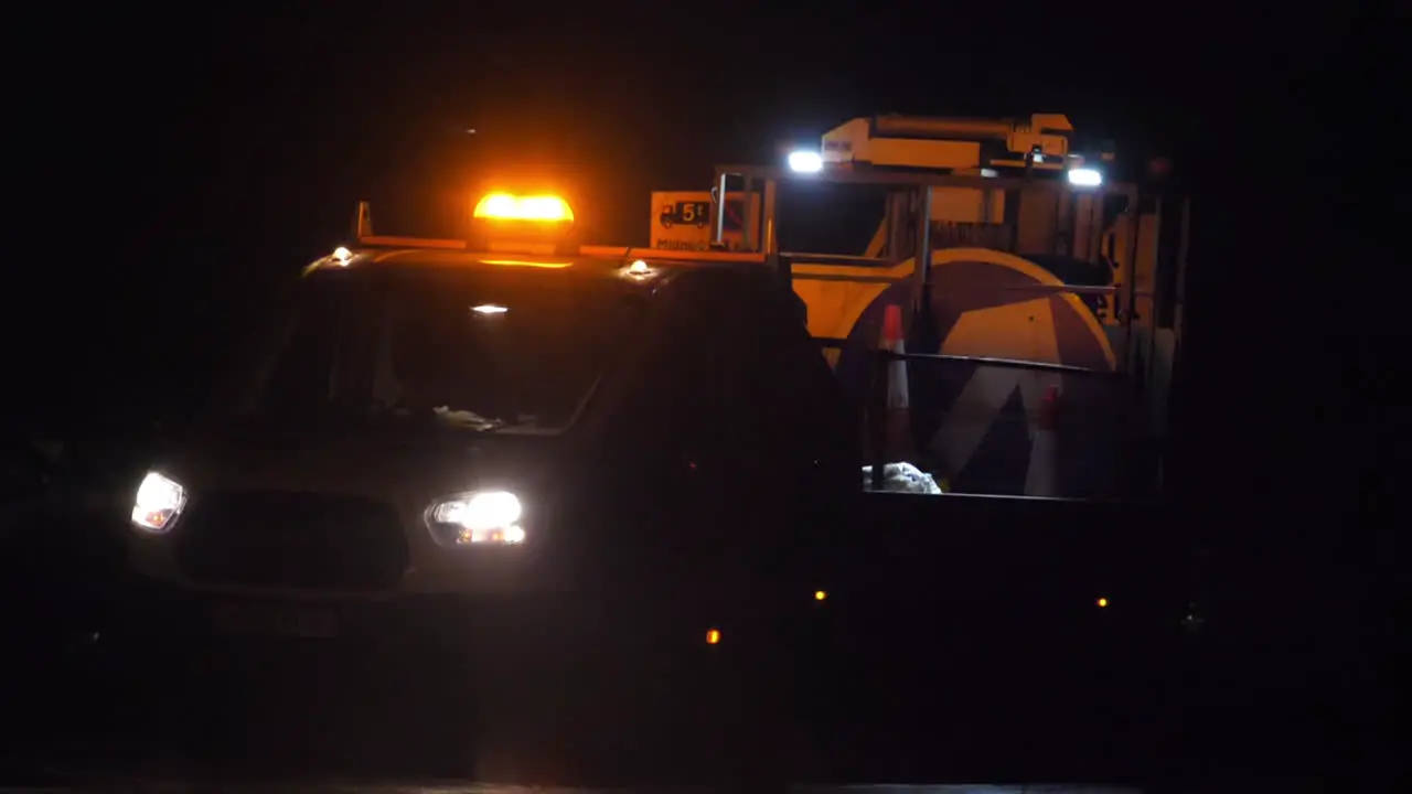 Slow motion shot of a UK roadworks van revealed from behind passing traffic at night