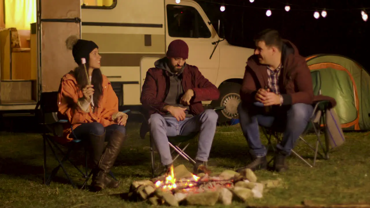 Group for friends singing together around camp fire