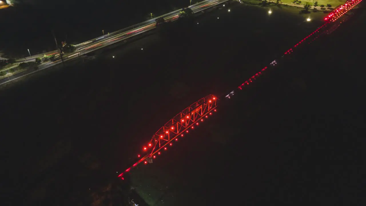 A drone aerial hyperlapse of a busy city at night with fast moving cars and a lit up bridge