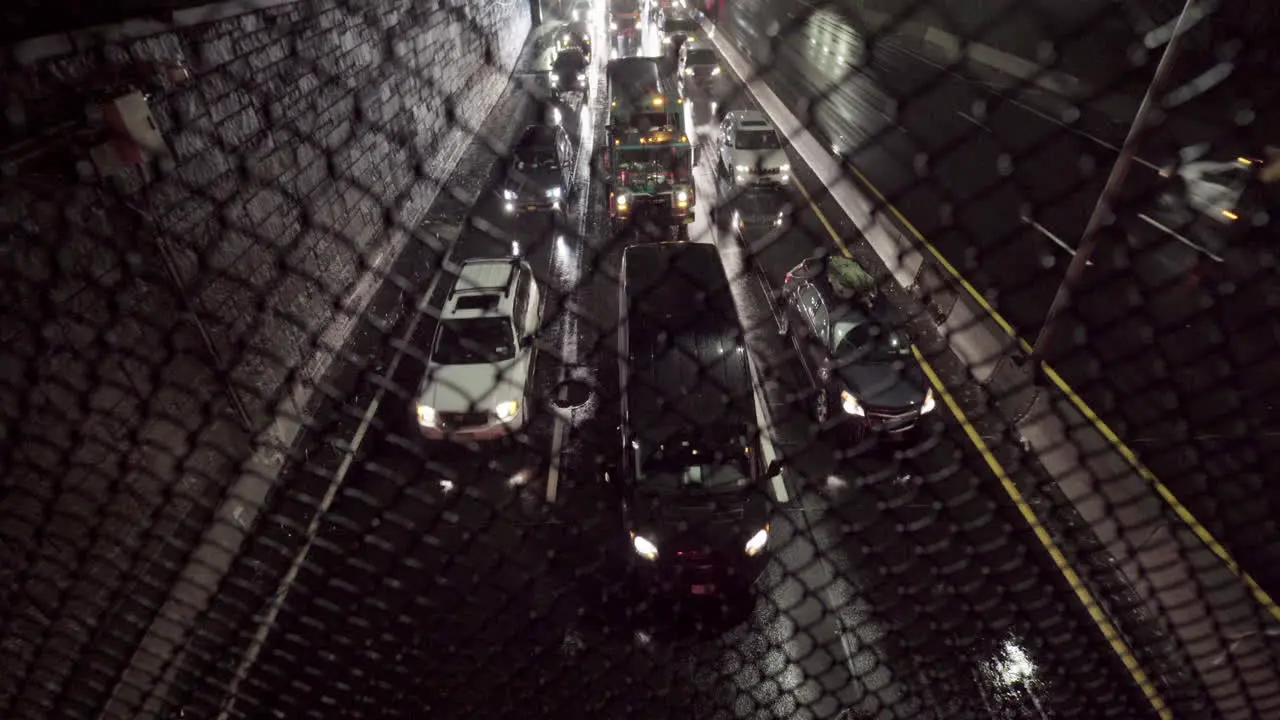 Slow Traffic on Highway at Night Under Heavy Rain Shot through Fence