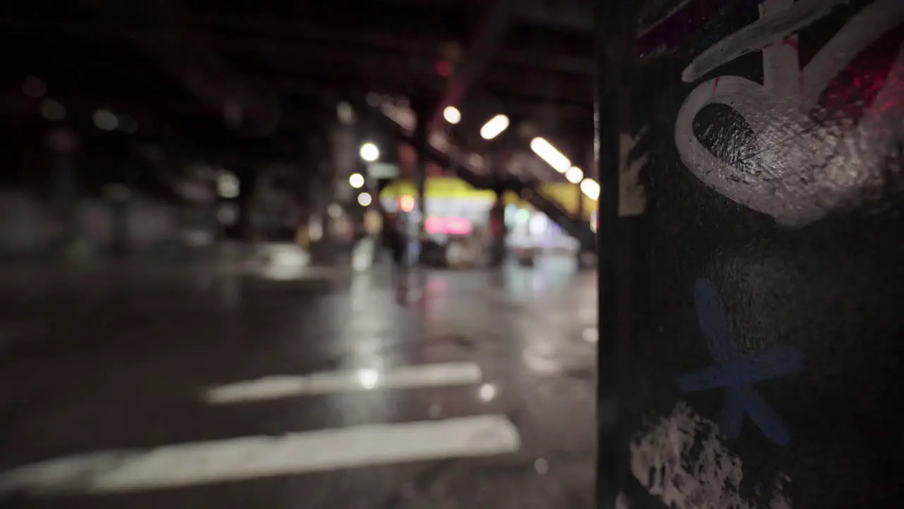 Dystopian Street Focus on Graffiti Steel Pole Out Of Focus Passerby Night