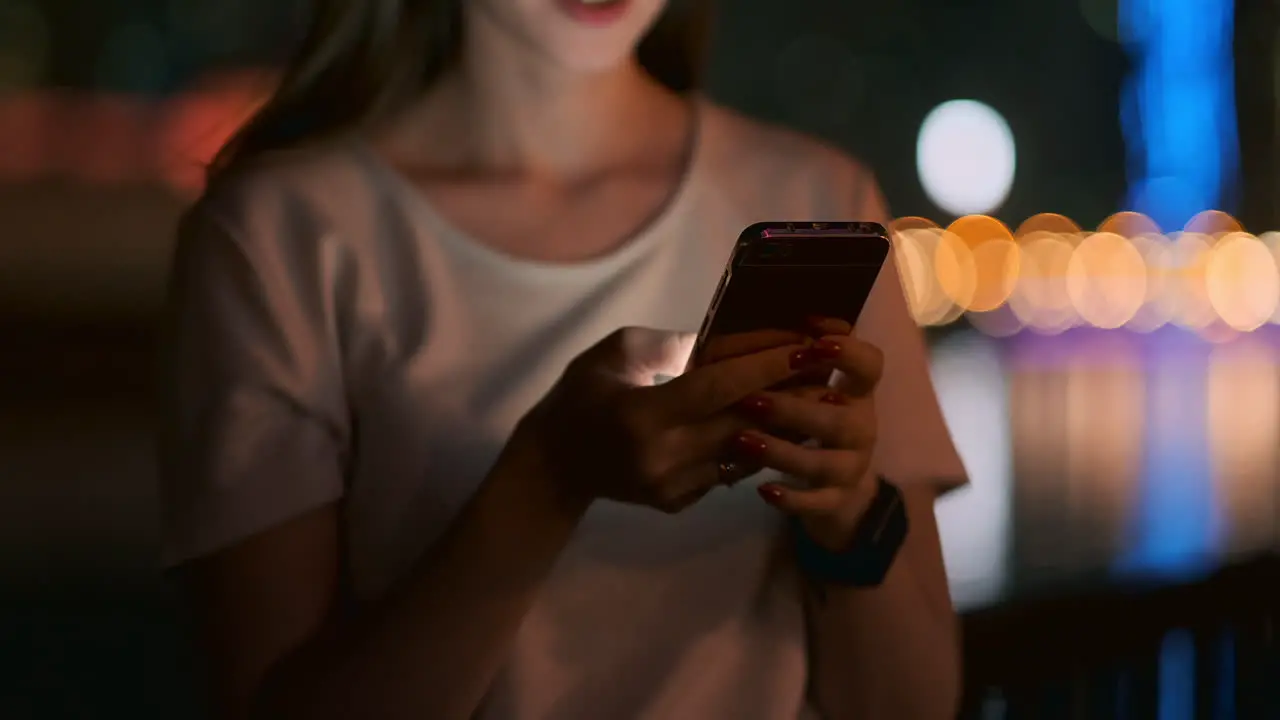 Close-up of a young girl holding a smartphone in Dubai at night and writing a text message