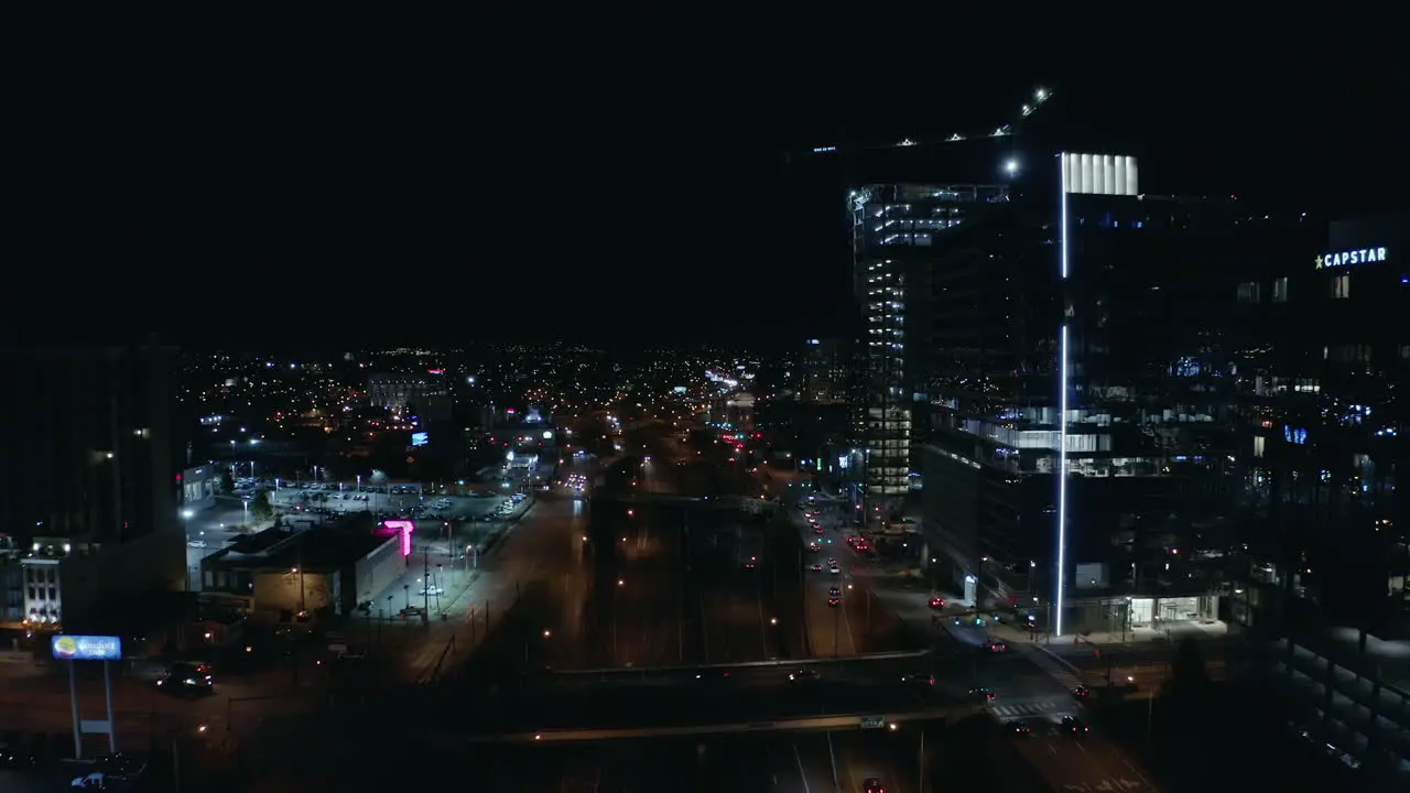 Night time aerial over dark highway in urban city with towers 4K