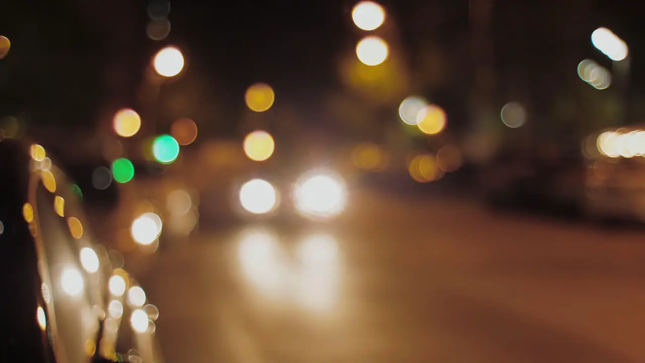 Blurred vision of city at night with traffic lights with a car passing by