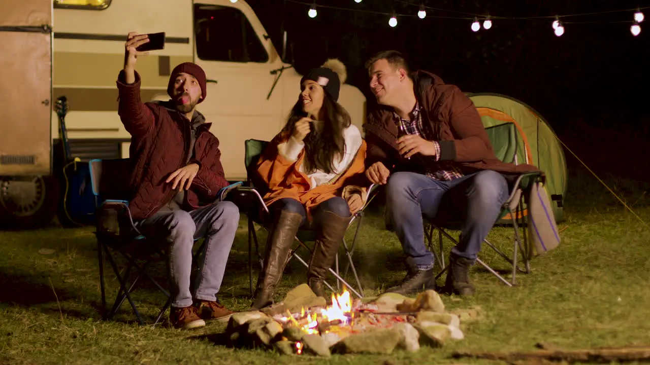 Close friends taking a selfie around camp fire