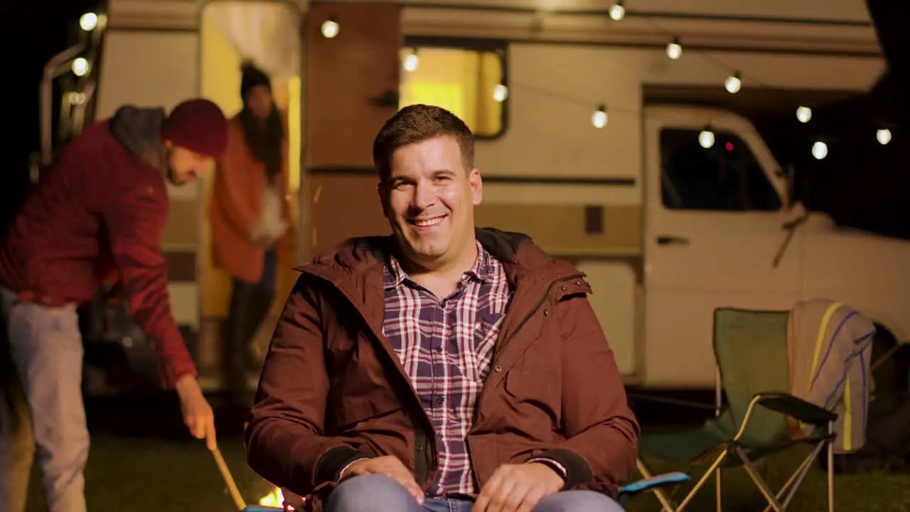 Happy young man sitting on camping chair looking at the camera